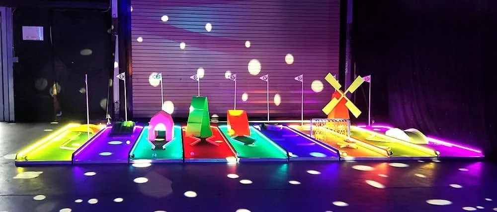 The indoor glow-in-the-dark mini golf course set up against a roller door